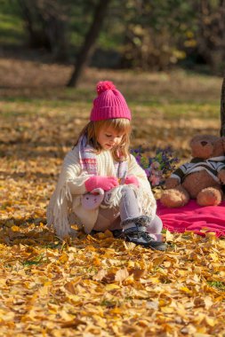 Sonbahar ayininde parlak renkli küçük bir kız oturuyor.