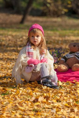 Sonbahar ayininde parlak renkli küçük bir kız oturuyor.