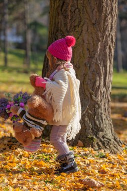 Sonbahar ormanında ayısıyla küçük bir kız.