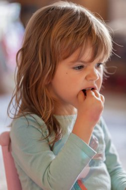 Küçük kız evdeki kaseden dondurma yiyor.