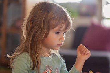 Küçük kız evdeki kaseden dondurma yiyor.