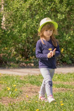 Kafasında şapkayla parkta yürüyen bir kız.