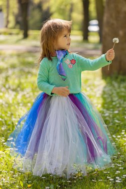 Kız karahindiba üflerken doğada poz veriyor.