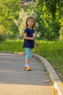 Çocuk parkta dondurma yalıyor.
