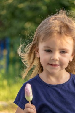 Çocuk parkta dondurma yalıyor.