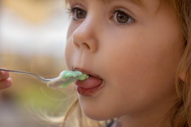 Küçük kız bardaktan dondurma yiyor. 