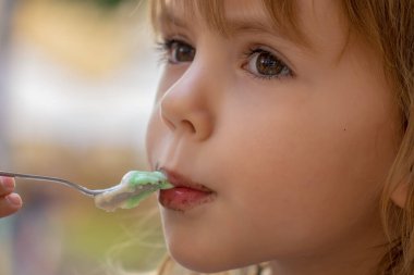 Küçük kız bardaktan dondurma yiyor. 