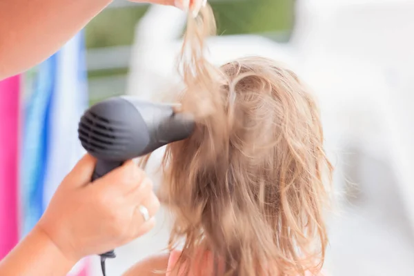 little girl\'s mother dries hair with hairdryer