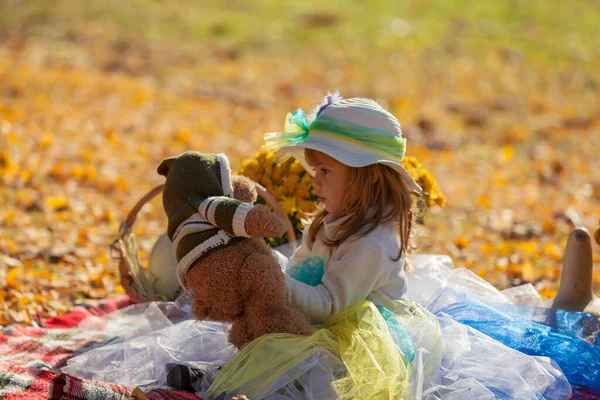 Sonbahar güneşinde şapkalı küçük kız Bea 'siyle oynuyor.