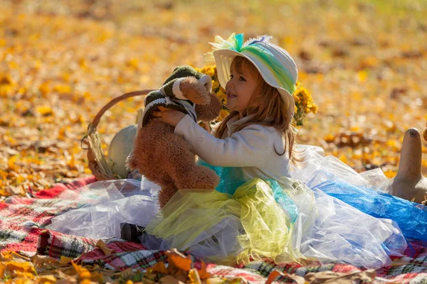 Sonbahar güneşinde şapkalı küçük kız Bea 'siyle oynuyor.