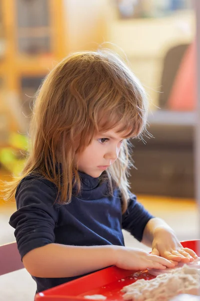 Küçük kız kinetik kum ve kalıplarla oynuyor.