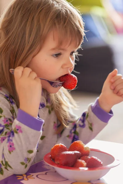 Çocuk kahvaltıdan sonra evde pijamalarıyla çilek yiyor.