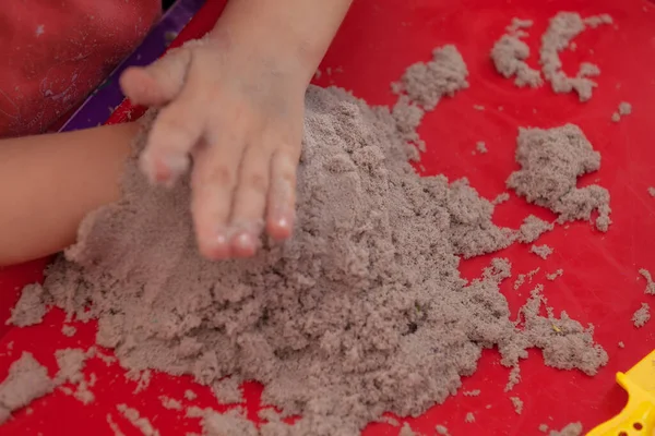 Kleine Hände Spielen Mit Kinetischem Sand Und Formen Auf Dem lizenzfreie Stockbilder