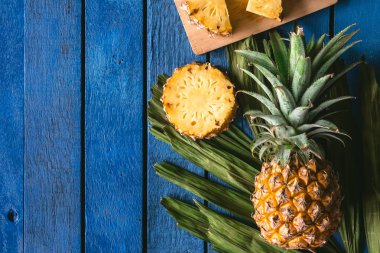 Mavi ahşap masa üzerinde üstten görünüm ananas meyve dilimleri ile. kopya alanı