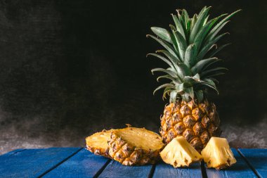 Siyah arka plan mavi ahşap masa taze ananas meyve. kopya alanı