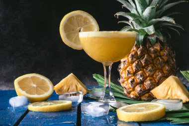 Mavi ahşap masa, siyah zemin üzerine limon ile ananas güler yüzlü