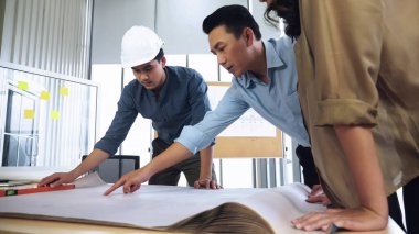 İnşaat alanında genç Asyalı mimarlardan oluşan bir ekip tartışıyor..