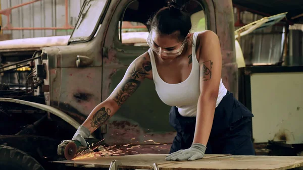 Attractive young woman mechanical worker repairing a vintage car in old garage.