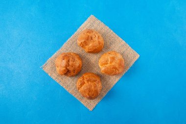 Mavi arka planda çuval bezi üzerinde taze altın çörekler. Üst görünüm, alanı kopyala.