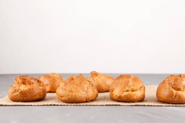 Hafif bir arka planda kremalı hamurdan taze altın çörekler (profiterol). Metin için yer.