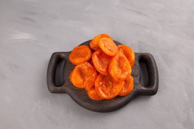 Tahta servis tabağında kurumuş kayısılar. Gri arka plan. Yukarıdan görüntüle, boşluğu kopyala.