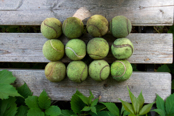 Старые, грязные теннисные мячи лежат на деревянной скамейке. Концепция - Спорт после пандемии коронавируса
.