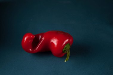 Konsept: Gıda atığı azaltma. Kusurlu ürünleri pişirmede kullanmak. Karanlık bir arka planda çirkin kırmızı dolma biber. Yakın plan, kopyalama alanı. 
