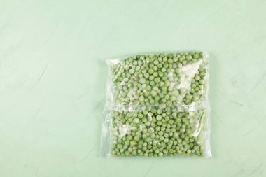 Frozen vegetables. Green peas in a transparent freezer bag. Light green background, copy space. clipart