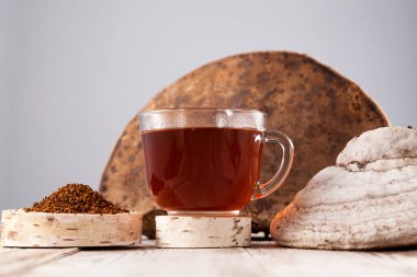 Chaga çayı - güçlü bir antioksidan, bağışıklık sistemini güçlendirir, detoks kalitesine sahiptir, sindirimi artırır. Huş ağacı mantarı ve toprak tozunun yanında temiz bir bardakta sağlıklı bir içecek. Kırsal biçim. 