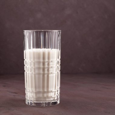 Kahverengi arka planda bir bardakta Ayran ya da kefir. Probiyotik soğuk mayalanmış süt içeceği. Kilo vermek için süt diyeti. Seçici odak, boşluğu kopyala.
