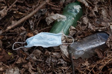 Coronavirus Covid-19 salgınından kaynaklanan yeni atık türleriyle çevre kirliliği. Kullanılmış yüz maskeleri ve plastik şişeler yere atılır..