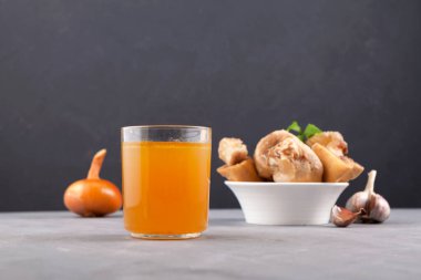 Koyu bir arka planda cam içinde ev yapımı haşlanmış sığır kemiği çorbası. Altın et bulyonu. Kemikler kolajen içerir.