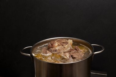 Et kemiği çorbası tencerede pişirilir. Karanlık arkaplan, kopyalama alanı. Kemikler, vücuda proteinlerin yapı taşları olan amino asitleri sağlayan kolajen içerir..