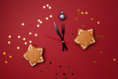 Yıldız şeklinde Noel kurabiyeleri ve kırmızı arka planda saat kolları. Yeni yıl kompozisyonu.