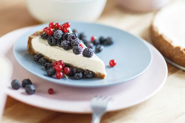 Slice of cheesecake with red currant and blackberries.