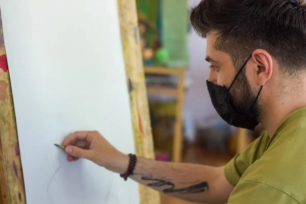 artist with black medical mask at work in a studio, artist with black medical mask painting picture