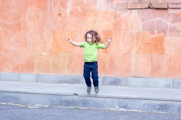 Счастливый Маленький Длинноволосый Мальчик Прыгает Парке — стоковое фото