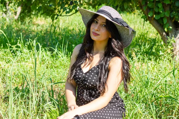Hasır Şapkalı Genç Kadın Bahçedeki Çimlerin Üzerinde Oturuyor — Stok fotoğraf