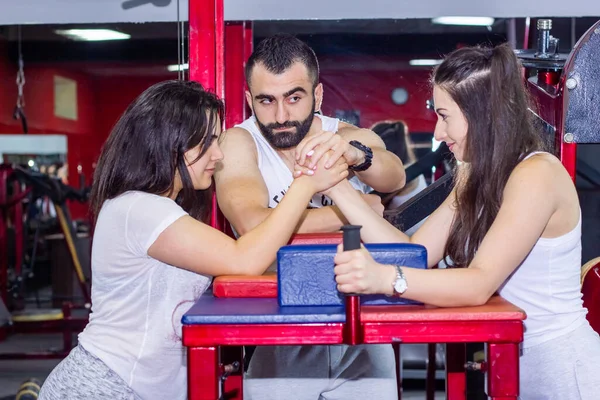 two young womans with trainer training in the gym