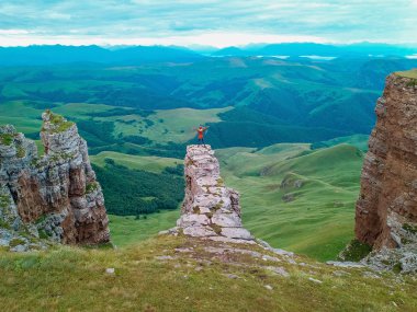 Drone havadan gelen görüntüleyin. Adam güneş doğarken Bermamyt Kuzey Kafkasya plato üzerinde amfitiyatro bir kaya üzerinde duruyor.