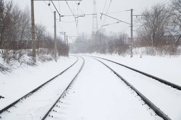 Şehirde kar yağışı. Karla kaplı raylar.