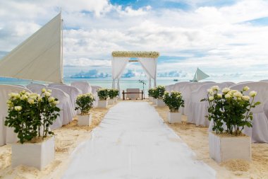 Beyaz bir tropik sahilde düğün töreni. Kemer kum plajındaki çiçeklerle süslenmiş, sandalye Konuklar, kumdan kale ve deniz yat için dekore edilmiştir. Düğün ve balayı konsepti.