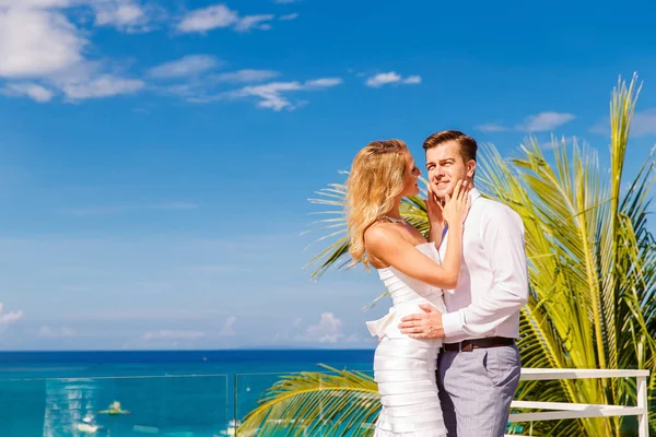 美丽的金发白色的婚纱礼服和酒店的屋顶上新郎新娘 热带海洋和棕榈树的背景 夏季度假概念 — 图库照片