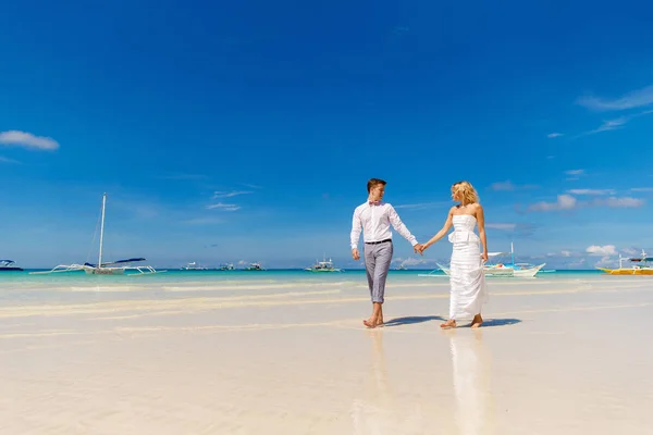 幸せの花嫁と花婿の熱帯のビーチで楽しい時を過します バック グラウンドで熱帯の海とヤシのボート 結婚式や新婚旅行のコンセプト — ストック写真