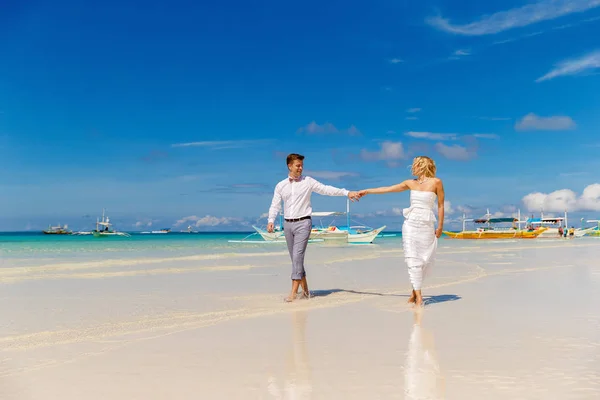 幸せの花嫁と花婿の熱帯のビーチで楽しい時を過します バック グラウンドで熱帯の海とヤシのボート 結婚式や新婚旅行のコンセプト — ストック写真