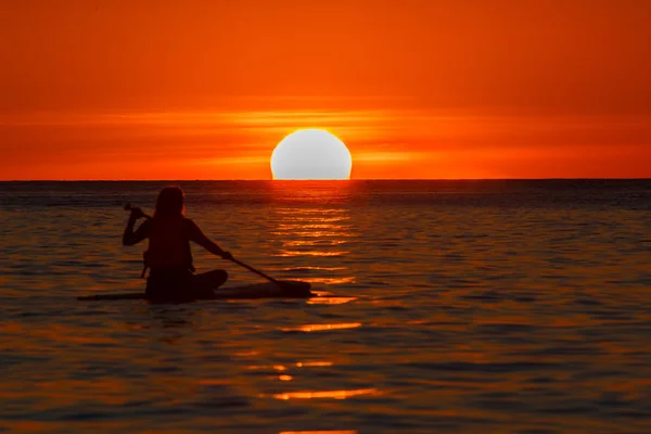 Silhouette photo of a man with a paddle on a paddleboard against — Stock Photo, Image