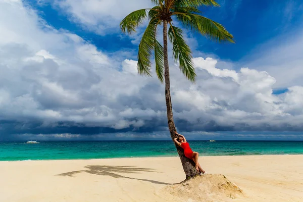 Dream scene. A girl in a red dress resting on a coconut tree on — Stock Photo, Image