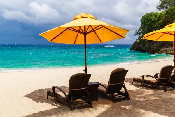 Sombrilla y camas de playa bajo las palmeras en bea tropical —  Fotos de Stock