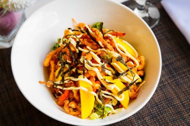 Ekmek kırıntılarında kızartılmış deniz ürünleri, sebze ve meyveli leziz salata. Beyaz bir tabakta servis ediliyor. Sağlıklı yemek..