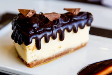 Çikolata soslu cheesecake ve beyaz tabakta servis edilen çikolata parçaları. Kapatın. Lezzetli atıştırmalıklar ya da bir dilim kek ile kahve zamanı..